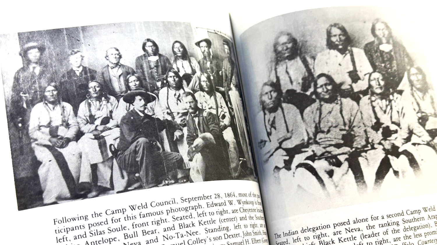 Open history book showing the iconic 1864 Camp Weld council photograph